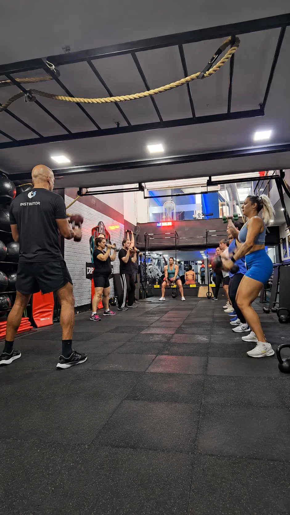 Victor Guilherme conduzindo uma aula funcional em grupo com alunos treinando com kettlebells.